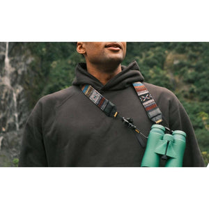 Person wearing Nocs Provisions green binoculars with a patterned woven strap