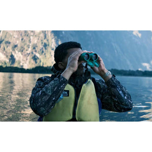 Person in a life vest using green NOCS Provisions binoculars on a lake
