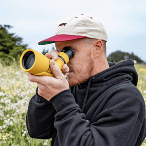 Person using a yellow NOCS Provisions monocular in a field