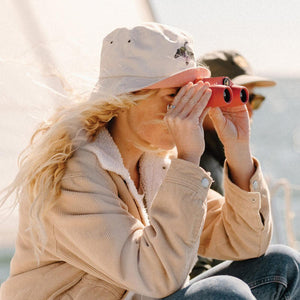 Person using red Nocs Provisions binoculars on a boat