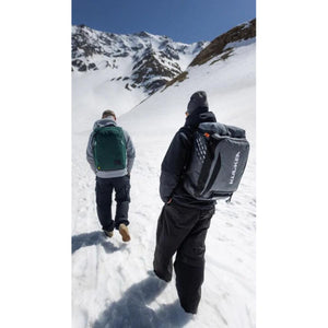Two people wearing Kulkea backpacks walking up a snowy mountain slope