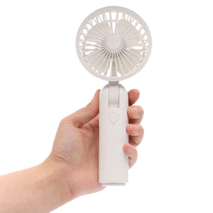 Hand holding a white Treva portable handheld fan