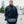 Man wearing a black ActionHeat heated vest with a hand warmer pouch in front of a city skyline