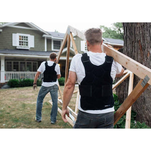 Two men wearing black Onyx Cool cooling vests while carrying wooden construction materials outdoors