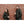 Man and woman wearing black ActionHeat hooded jackets standing against a brick wall holding coffee cups