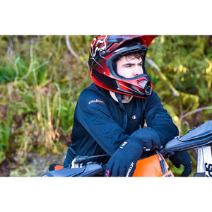 Person wearing ActionHeat black long sleeve shirt and gloves with a red motocross helmet leaning on a motorcycle