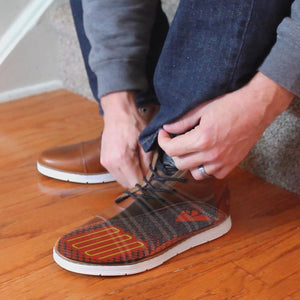 Person adjusting ActionHeat heated brown leather boots with visible internal heating elements