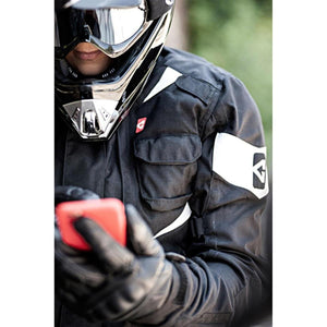 Motorcyclist wearing a black Gerbing jacket and helmet using a smartphone