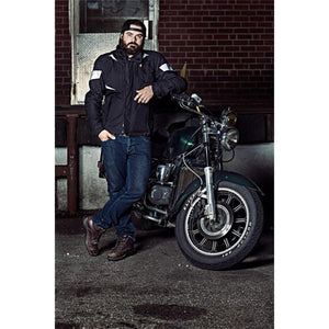 Man wearing a black Gerbing motorcycle jacket leaning against a motorcycle