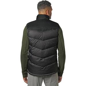 Back view of a man wearing an Outdoor Research black quilted puffer vest over a green long sleeve shirt