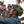 Cyclist wearing an olive green helmet and Outdoor Tech bone conduction headphones drinking from a water bottle