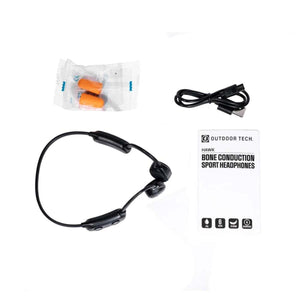Outdoor Tech Hawk bone conduction headphones with charging cable, earplugs, and product manual