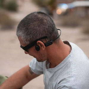 Person wearing black Outdoor Tech bone conduction headphones