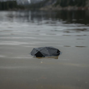 Outdoor Tech black geometric portable speaker floating in water