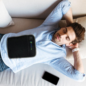 Man lying on a sofa with a HealthyLine heating pad on his stomach