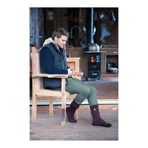 Man sitting in wooden chair wearing Heat Holders thermal socks