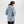 Woman wearing a light blue Outdoor Research hooded rain jacket viewed from the back