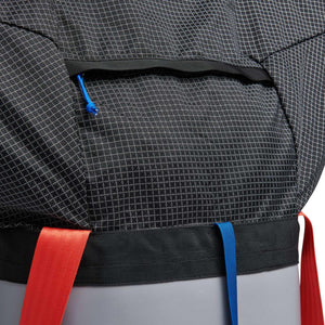 Black Diamond backpack detail showing grid fabric texture, zipper pocket, and red and blue webbing straps