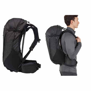 Black Thule hiking backpack shown empty and worn by a person from the side