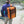 Person wearing an orange Polar Bear Coolers backpack cooler while walking down wooden steps near a river
