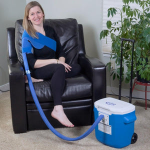 Woman wearing a Polar Products shoulder cold therapy wrap connected to a portable cooler unit