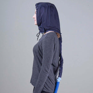 Person wearing a dark blue cooling therapy head wrap with a connected hose