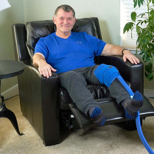 Man sitting in a recliner wearing a Polar Products blue knee cold therapy wrap