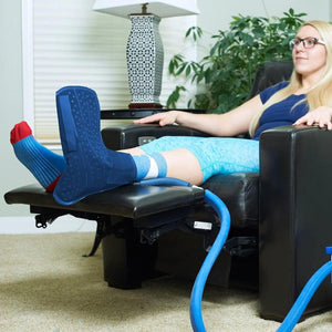 Person wearing a blue cold therapy ankle wrap while resting in a recliner