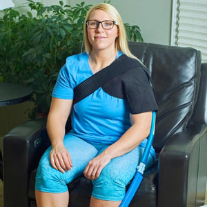 Woman wearing a Polar Products black shoulder ice wrap while sitting in a chair