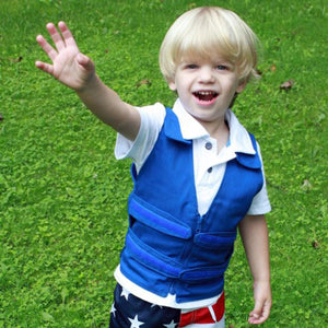 Young boy wearing a blue compression vest over a white polo shirt and star patterned shorts