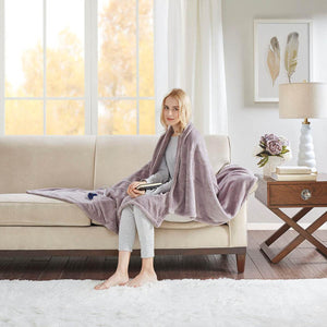 Woman sitting on a sofa draped in a purple Beautyrest heated throw blanket