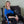Woman wearing a blue Polar Products shoulder ice pack wrap while sitting in a leather chair