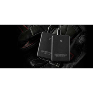 Two black REV IT Thermotronic heating technology battery packs resting on black leather gloves