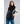 Woman wearing a black 8K FlexWarm puffer vest over a grey sweater and blue jeans