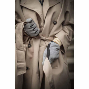 Person wearing grey Hestra gloves with a beige trench coat