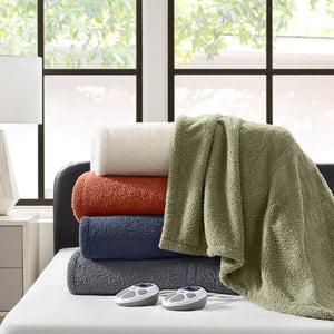 Stack of folded Serta heated blankets in various colors on a bed