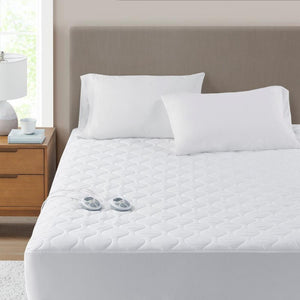 Serta white quilted electric mattress pad with two remote controllers on a bed