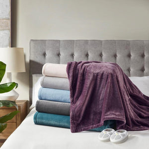 Stack of folded Serta plush heated blankets in various colors on a bed