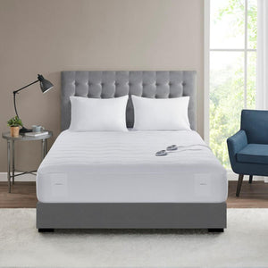 Serta heated mattress pad on a bed with two white pillows and two controllers