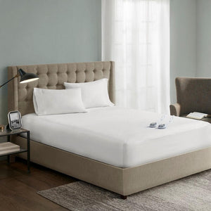 Serta white heated mattress pad on a bed with a tufted headboard