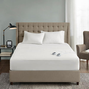 Serta heated mattress pad on a bed with two white pillows and two remote controllers