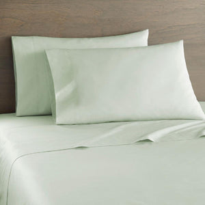 Shavel light green bed sheet set with two pillows against a wooden headboard