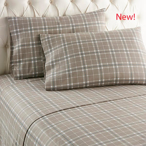Shavel tan plaid bed sheets and pillowcases on a tufted headboard