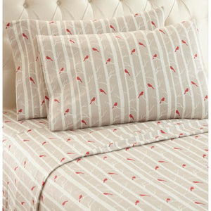 Beige bed sheets and pillowcases with a red cardinal and white birch tree pattern