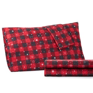 Red and black buffalo plaid pillowcase and folded sheet set with white snowflake pattern