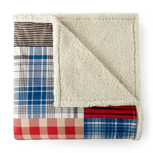 Folded patchwork throw blanket with plaid and striped patterns and cream sherpa lining