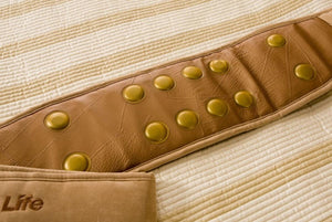 Shield Life brown leather belt with embedded circular gold discs on a quilted fabric surface