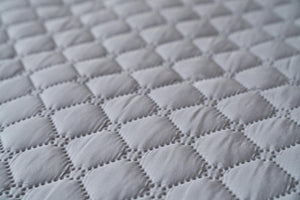 Close up of grey quilted fabric with diamond pattern