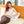 Woman sitting on a Shield Life heating pad adjusting the handheld controller