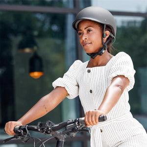 Woman wearing a helmet and Shokz bone conduction headphones while riding a bicycle